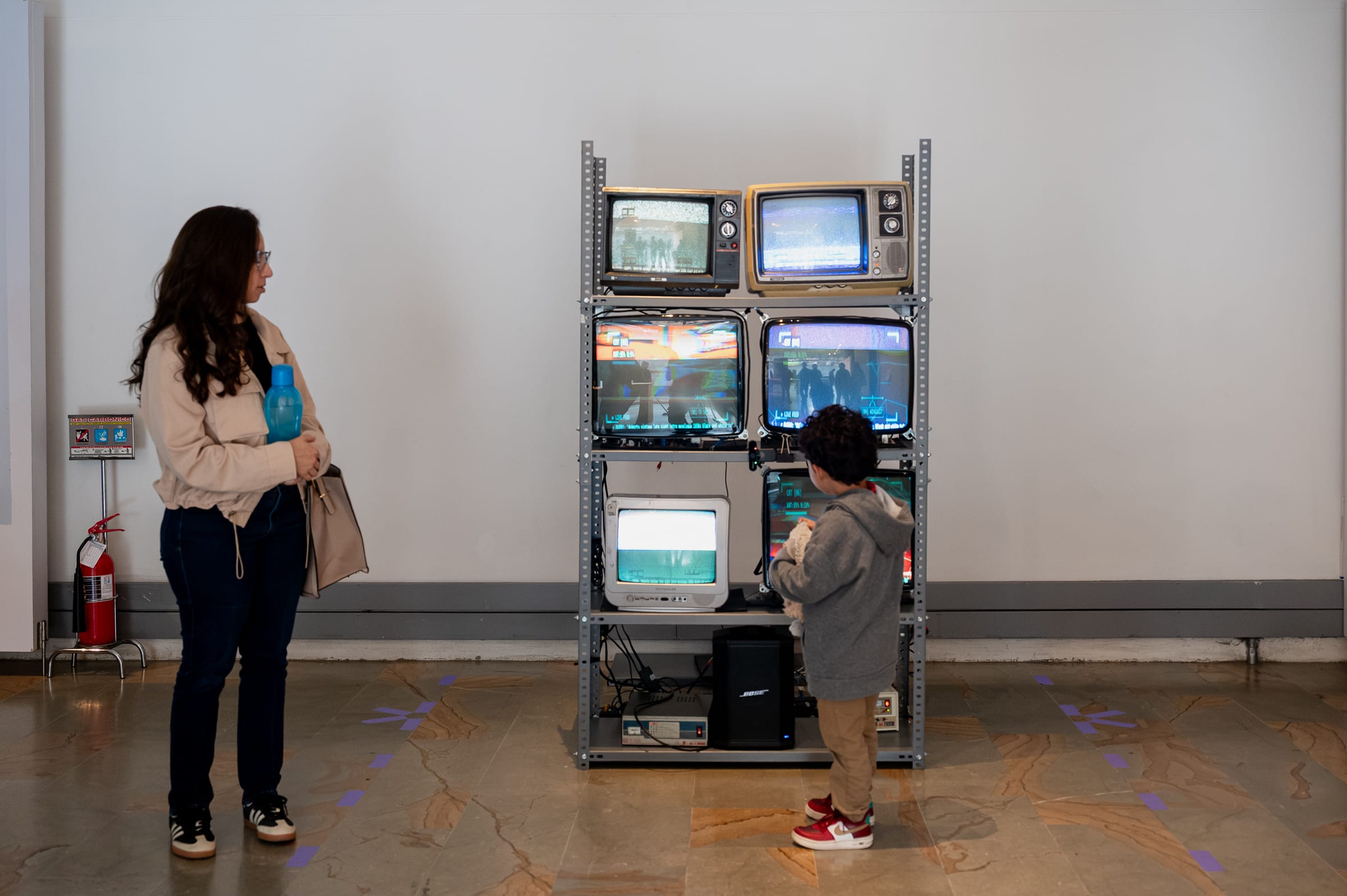 A woman and a young child inspecting the 6-CRT totem at close range in the exhibition space